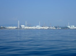 View of a nuclear power plant from the water, showcasing its structure and surrounding landscape.