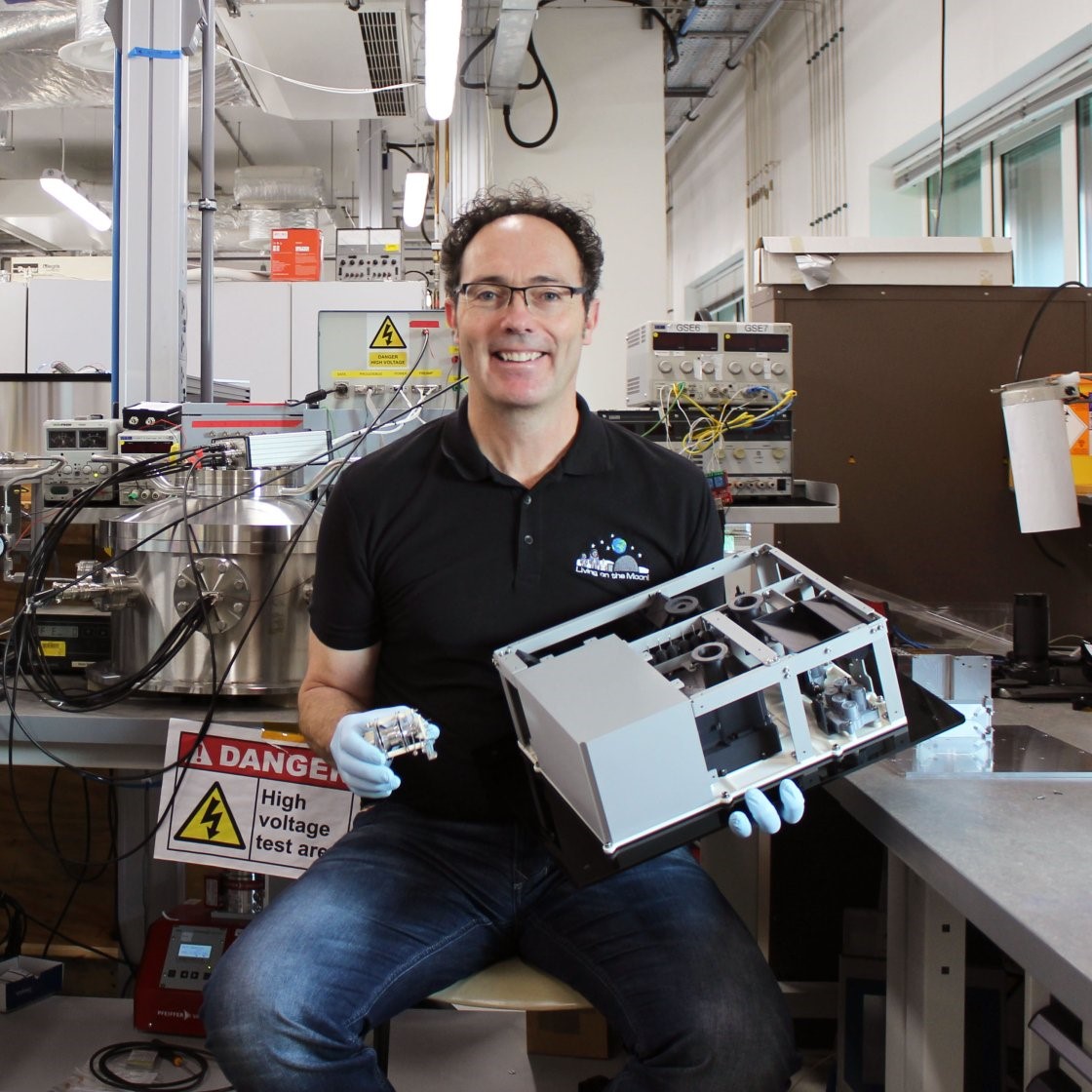 Feature image A man in a lab sits holding a small electronic device, focused on its features and functionality.