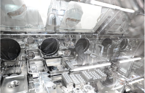 A man in a lab coat examines a complex machine, focused on its components and functionality