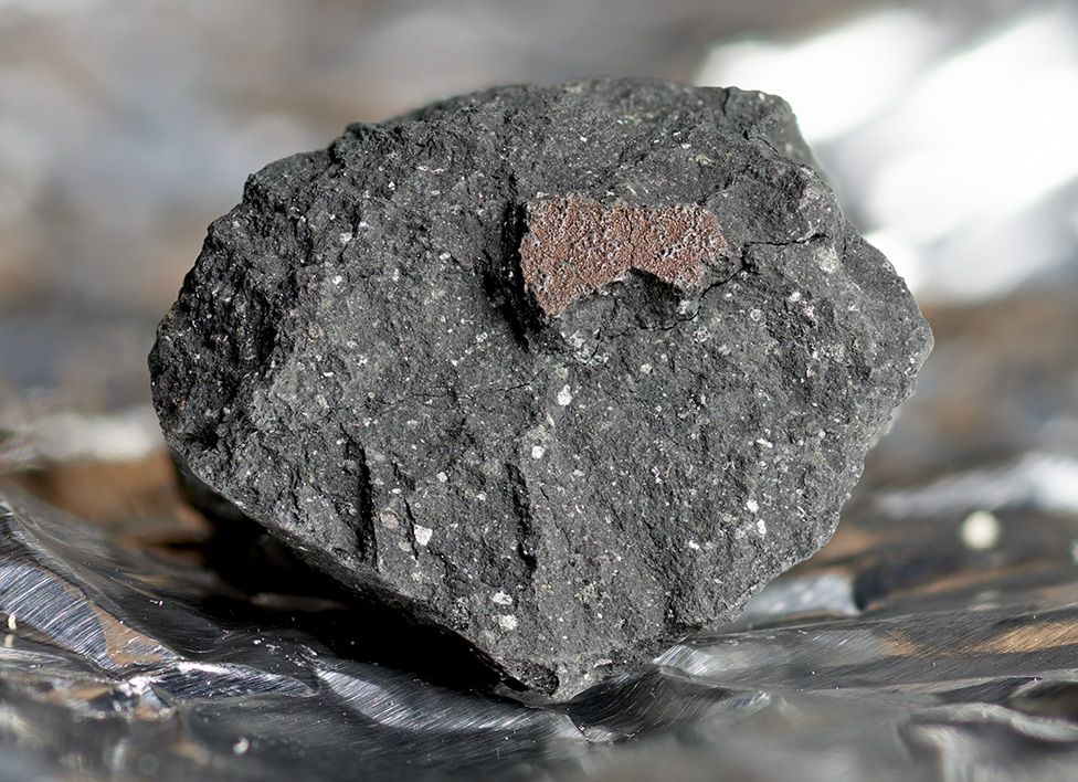 A rock with a small piece of metal resting on its surface, showcasing a contrast between natural and man-made materials