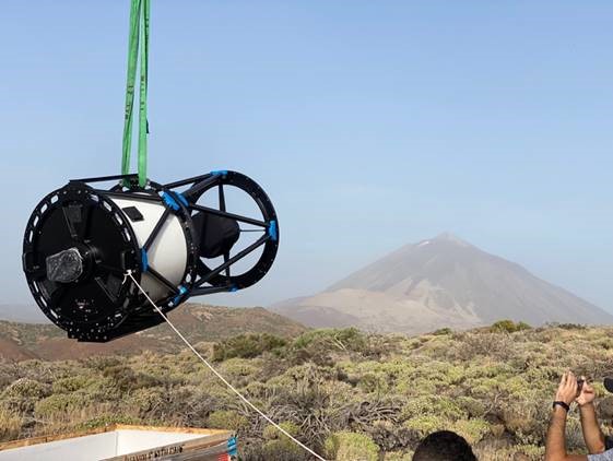 A man holds a camera up, preparing to take a photograph outdoors.