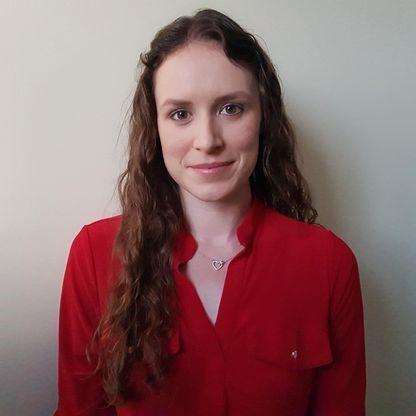 Feature image A woman with long hair is wearing a bright red shirt, standing against a neutral background.
