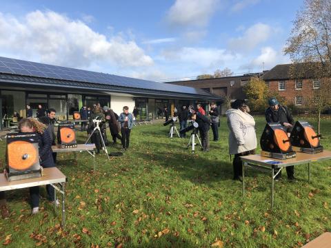 People gathered around tables displaying solar panels, discussing renewable energy solutions and technology advancements.