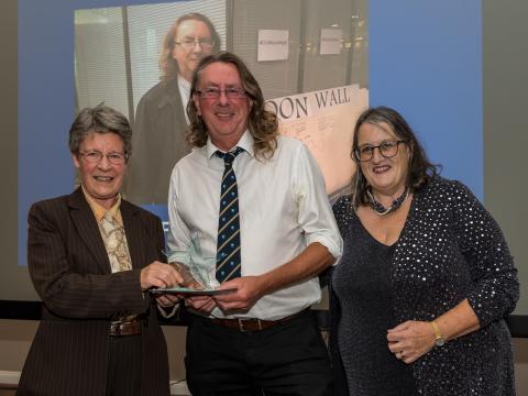 Three individuals celebrate as one holds the award for Best Speaker, showcasing their achievement and camaraderie.